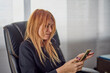 © czamfir - portrait of a woman sitting at the desk and writing a message on her phone