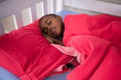© wavebreak3 - Child sleeping peacefully in bed with red blanket, resting comfortably at home, copy space