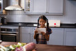 © wavebreak3 - Young girl in kitchen smiling while using tablet, surrounded by fresh vegetables, copy space