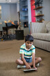 © wavebreak3 - Young boy sitting on carpet using tablet at home, focused on screen, copy space