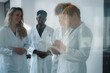 © DusanJelicic - Smiling diverse medical students and a professor, wearing lab coats, collaborating on a research project while reviewing data on a clipboard and tablet in a modern laboratory