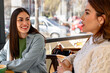 © we.bond.creations - Two young women talking and drinking coffee in a bar