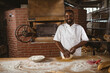 © Wavebreak Media - Kneading dough, smiling baker in rustic bakery with brick oven and flour, copy space