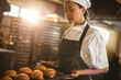 © Wavebreak Media - Female baker carrying tray of freshly baked croissants in bakery kitchen, copy space