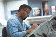 © Wavebreak Media - Designer in denim shirt sketching at drafting table in modern office