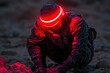© Galina - Soldier in futuristic gear kneeling on rocky terrain with red illuminated helmet at dusk