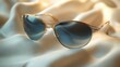 © sadewotito - Elegant aviator sunglasses with gold frame and pearls, resting on luxurious silk fabric.