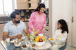 © GAJENDRRA BHATI  - indian family having breakfast together at home. mother making cereal with milk in bowl for her daughter.