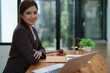 © Jirapong - female attorney advisor at a law firm reviews legal documents at her desk equipped with a laptop notebook and scales of justice in the office