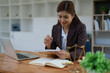 © Jirapong - female attorney advisor at a law firm reviews legal documents at her desk equipped with a laptop notebook and scales of justice in the office