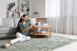 © Pixel-Shot - Beautiful young woman in headphones with mobile phone sitting on floor at home