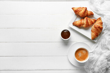 Wall Mural - plate with tasty croissants and cup of coffee on white wooden background