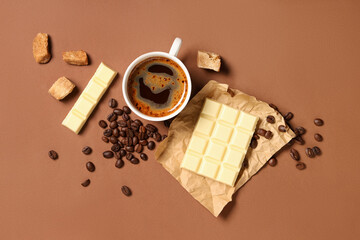 Wall Mural - White sweet chocolate with cup of coffee and beans on brown background