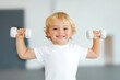 © TATIANA Z - Smiling young boy in a white t-shirt lifting small dumbbells in a bright fitness studio, showing enthusiasm and energy