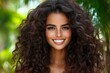 © Thammarong - A confident young woman with deep brown eyes and curly hair, smiling radiantly in a lush green park