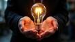 © hathairat - Bright Light Bulb in Hands Symbolizing Innovation and Ideas