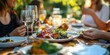 © MNStudio - Group of cheerful friends having fun at garden party. Eating dinner together by decorated table. Young people having a get together on summer evening.