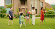 © Raushan_films - Indian happy mom hold hose pipe spray water on house lawn park tree young adult family teen girl dad cute son kid boy child male man female group play ball game have fun joy spend day time enjoy trip