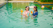 © Raushan_films - India happy wet woman lady with teen age girl dancing in pool hold glass drink fresh juice outdoor luxury resort Young adult mom female child have fun joy enjoy day spend time water park hotel villa