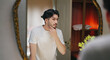 © Raushan_films - Indian Asian gen z young adult single happy man male guy smiling look mirror touch beard daily care routine good ready for new Joyful day enjoy indoor house