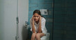 © Raushan_films - Indian young adult gen z woman lady sitting on toilet bowl hold belly have health issues upset teen age girl female feel bad hurt unwell facing ache period cramp pain food poison indoor home house