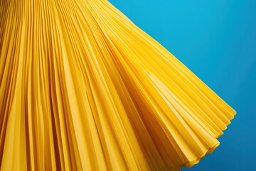 Poster - Bright yellow pleated fabric cascades elegantly against a vibrant blue background