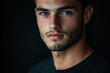 © Sadia - Close up portrait of a young man with a beard and freckles against a dark background looking at the camera