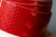 © DRBURHAN - Close-up of red reflective safety tape roll  A detailed close-up of a roll of red reflective safety tape with a hexagonal pattern, commonly used for visibility, road safety, and hazard marking.