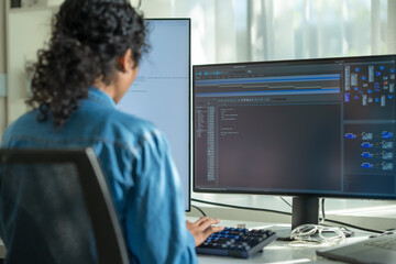 An Asian woman sits at her office desk, typing detailed prompts for an AI application, merging her expertise in programming with her passion for technology and security.

