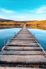 Wall Mural - Rustic wooden bridge stretching over tranquil lake under clear blue sky in serene landscape