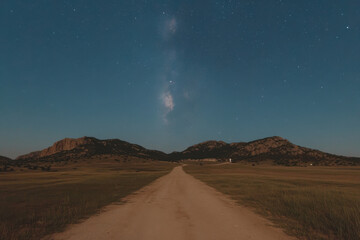 Wall Mural - A road in the middle of a field with a large hill in the background