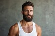 © Viktor - Handsome man with a beard in white tank top posing. Portrait of adult male looking at camera. Stylish hipster with modern hairstyle and grey mustache, casual urban lifestyle.