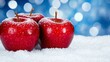© STK - Three red apples dusted with snow sit on a snowy surface against a blue bokeh background.