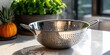 © bborriss - Metal colander sitting on kitchen counter with fresh herbs and pineapple in background