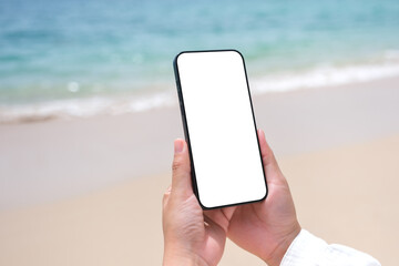 Wall Mural - mockup image of a woman holding mobile phone with blank desktop screen by the sea