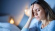 © umut hasanoglu - Woman in distress with a headache and fatigue touching her forehead in bed at night Concept of discomfort illness stress and sleep issues