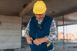 © Ljustina - Senior construction worker pulling utility knife from pocket inside building shell