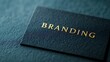 © Tanakrit - A close-up of a textured black business card with the word 'BRANDING' elegantly embossed in gold.