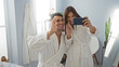 © Krakenimages.com - Man and woman smiling in spa taking a selfie in robes, capturing joyful moment in a wellness center's relaxing interior with bright lighting and modern decor.