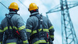 © Tanakrit - Two power workers in safety gear observe high voltage lines, showcasing their teamwork and dedication to electrical safety and maintenance.
