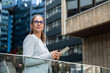 © Srdjan - Portrait of a successful business woman using digital tablet in front of modern business building. Businessperson office worker design professional occupation, innovative work outside of workspace.