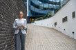 © Srdjan - Portrait of a successful business woman using digital tablet in front of modern business building. Businessperson office worker design professional occupation, innovative work outside of workspace.