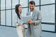 © Srdjan - Two businesspeople standing outside of modern office building using digital tablet working on new project discussing and explaining business matters and smiling. Design professional occupation persons