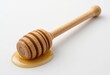 © GL - Wooden Honey Dipper Resting on Golden Honey Puddle Isolated on White