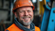 © Vasiliy - Smiling construction worker with beard wearing orange safety helmet and vest. Industrial portrait concept for engineering companies, safety training and labor recruitment