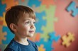 © miss irine - Little boy with autism spectrum disorder smiles looking away. Puzzle pieces in background. World Autism Awareness Day. Child mental health, support, understanding. Autism, ASD concept.
