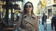 © AI Art - A fashionable young woman walking through a city street wearing a stylish trench coat and sunglasses.