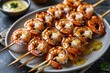 © Naeem 2.0 - Succulent grilled shrimp skewers glistening with a zesty sauce, a delightful summer feast presented on a rustic plate with warm lighting.