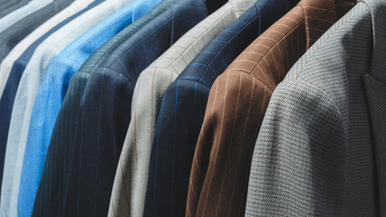 Poster - A row of suits hanging on a rack, with the blue suit on the left and the brown suit on the right