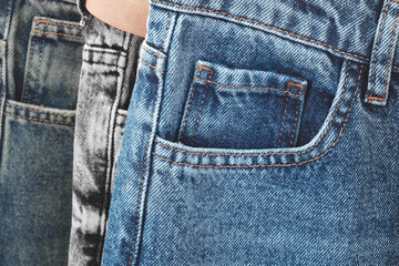 Poster - A pair of jeans with a pocket and a person's arm showing the pocket. The jeans are blue and gray